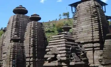 Serene pine forest landscape near Jageshwar Dham in Uttarakhand with rolling green hills and distant Himalayan town view.