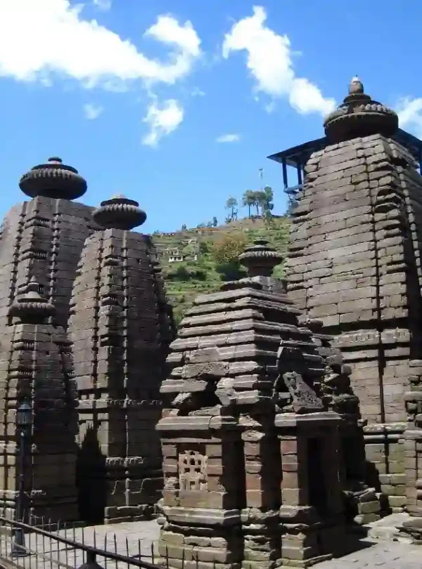 Serene pine forest landscape near Jageshwar Dham in Uttarakhand with rolling green hills and distant Himalayan town view.