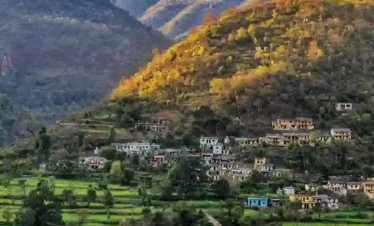 Picturesque village landscape near Jageshwar Dham in Uttarakhand with terraced green fields, hillside homes, and sunlit mountain slopes.