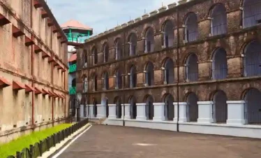 Historic Cellular Jail wing in Port Blair, Andaman, showing the multi-story brick architecture with arched corridor windows and iron bars under a blue sky.