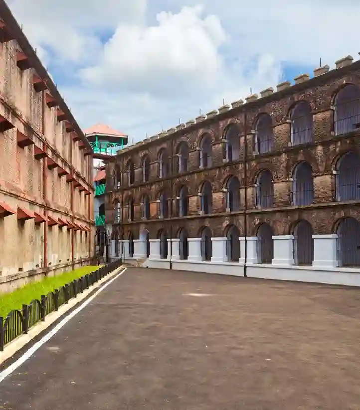 Historic Cellular Jail wing in Port Blair, Andaman, showing the multi-story brick architecture with arched corridor windows and iron bars under a blue sky.