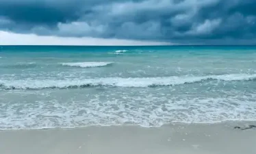 Stormy, overcast skies over a turquoise ocean and white sand beach at Havelock Island.